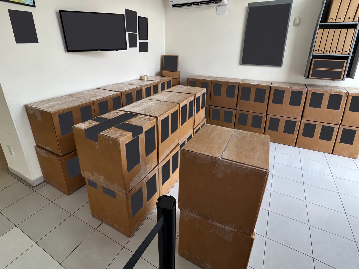 Bulk shipping cartons arranged at a carrier location, with shipping labels and Spanish signs concealed