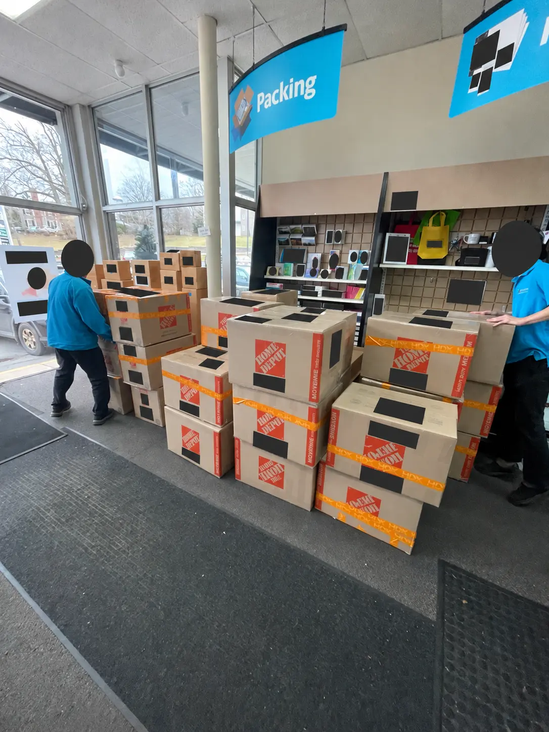 Shipping cartons staged at a carrier counter, with faces and shipping labels concealed